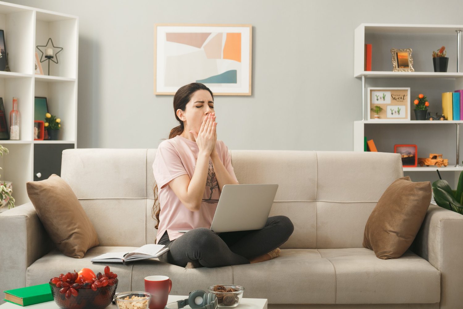 woman sitting on couch and covering her nose with hands, she might be smelling something must odor in her house.