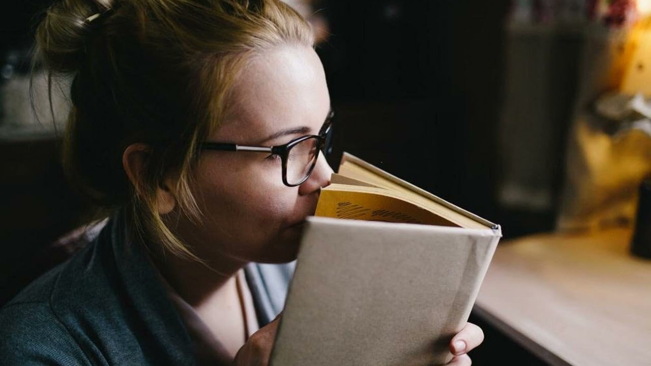 a woman smelling book.